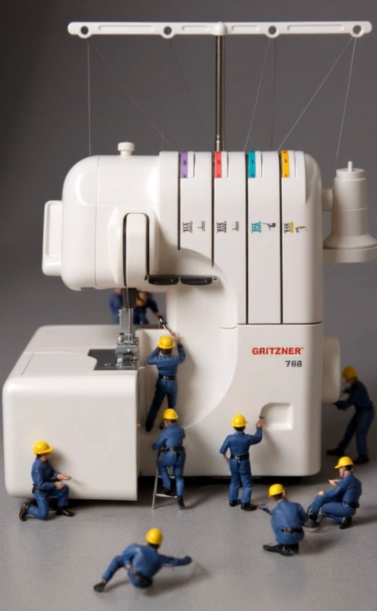 Miniaturarbeiter in blauen Uniformen und gelben Helmen erscheinen, um eine große weiße Nähmaschine zu reparieren oder zu inspizieren. Sie illustrieren kreativ die Teamarbeit bei der Wartung / Reparatur Gritzner 788 Overlock von GRITZNER-Shop.