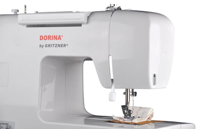 Eine weiße DORINA 323 Nähmaschine von GRITZNER-Shop mit Stoff unter der Nadel, bereit zum Nähen, vor einem schlichten weißen Hintergrund.