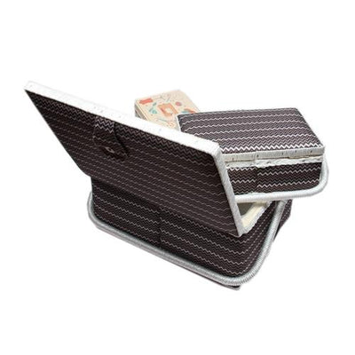 Eine teilweise aufgeklappte braun-weiße Faltmatratze mit weißer Paspel hält ein GRITZNER-Shop Nähkorb-Set bunt weiß, braun, schwarz (1x groß, 1x mittel) und eine Accessoires Box (mit Zubehör); die Matratze ist außerdem mit einem Tragegriff ausgestattet.